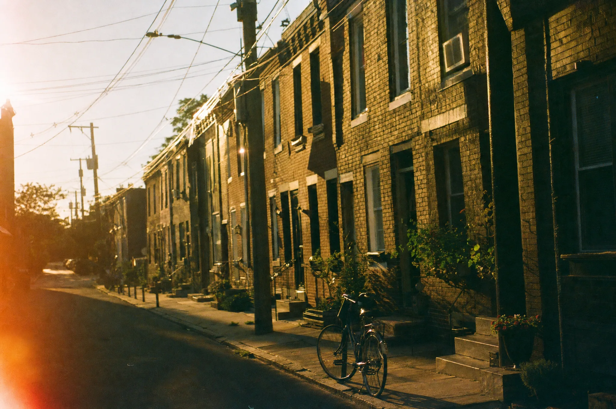 Brick rowhouses on a Fishtown side street at golden hour, shot on color film